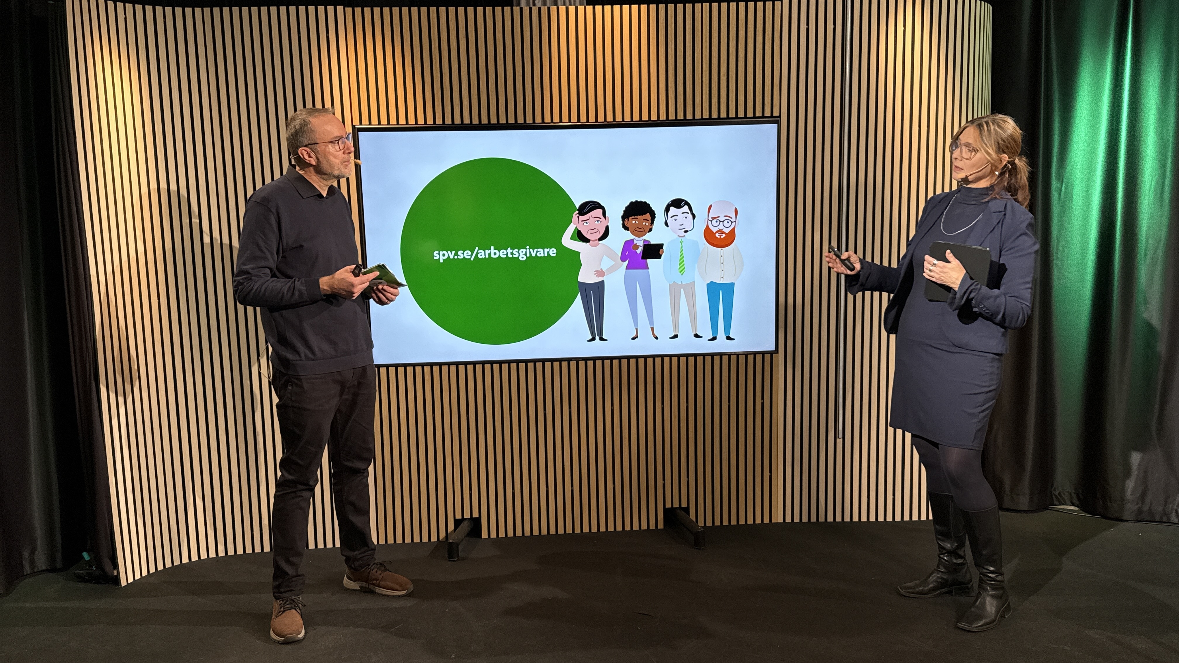 En man och en kvinna står och föreläser vid en stor bildskärm