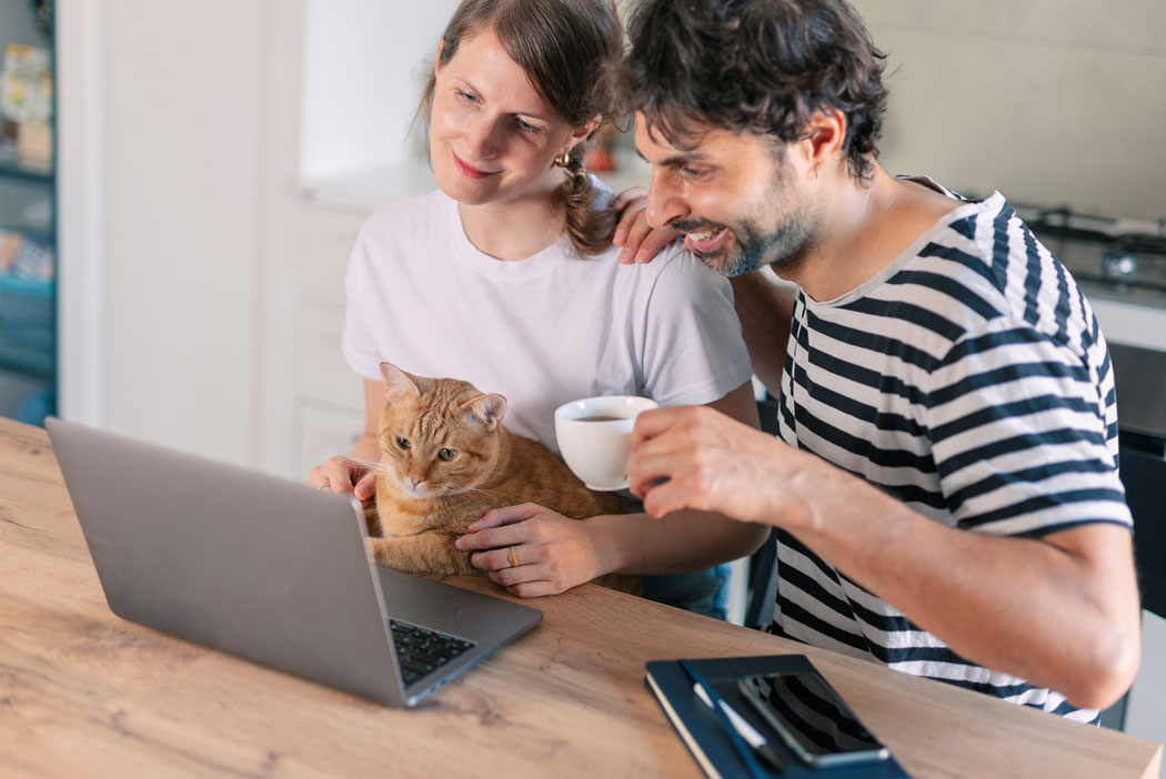 Man och kvinna med katt framför en dator